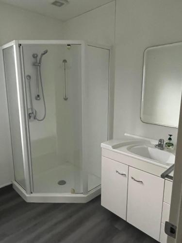 a white bathroom with a shower and a sink at Sherwood Ranch Cottages - 405 Woodbank Road in Hanmer Springs