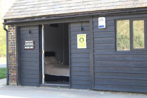 un pequeño cobertizo azul con una cama. en The Stables Lodge Stansted, en Takeley