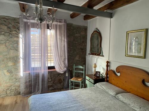 1 dormitorio con 1 cama y ventana con silla en Loft Rural Con Encanto, en La Coromina
