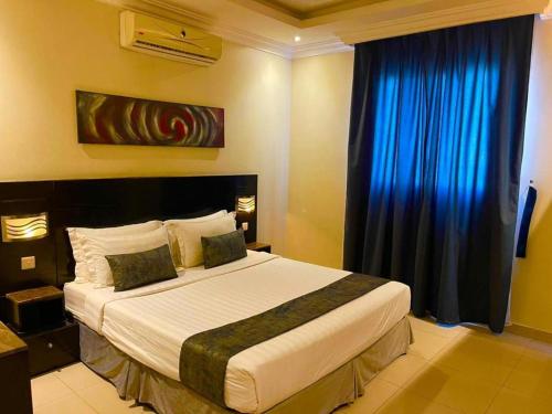 um quarto com uma cama grande e cortinas azuis em سكن للمسافرين em Dhamār