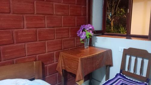 una mesa con un jarrón de flores púrpuras. en Hospedaje Los Balcones Jumbilla Bongará Amazonas, 