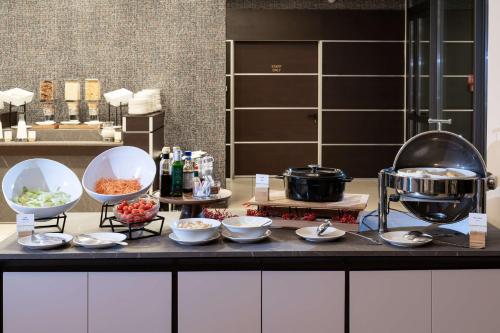 a buffet with bowls of food on a counter at Doubletree by Hilton Milan Malpensa Solbiate Olona in Solbiate Olona