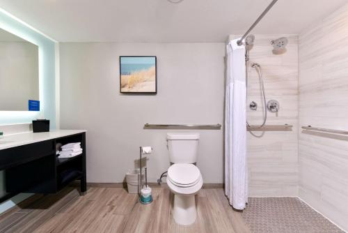y baño con aseo blanco y ducha. en DoubleTree by Hilton Corpus Christi Beachfront, en Corpus Christi