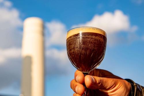 a hand holding a cup of homebrew at art'otel London Battersea Power Station, Powered by Radisson Hotels in London