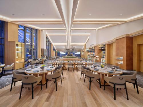 a dining room with tables and chairs and windows at DoubleTree by Hilton Changbaishan Hot Spring in Antu