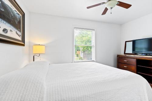 a white bedroom with a bed and a flat screen tv at Lakeview on the Lake in North East