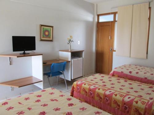 a hotel room with two beds and a desk with a computer at Picos Hotel in Picos