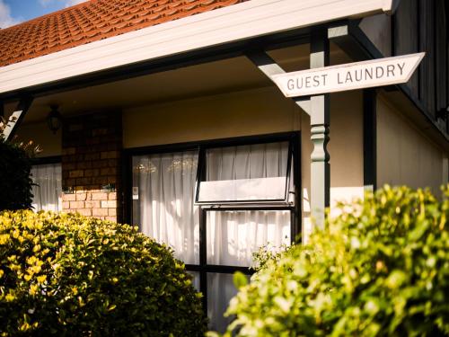 a guest laundry sign in front of a house at Tudor Court Motor Lodge in Auckland