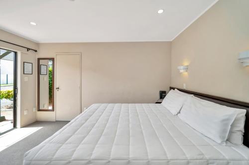 a large white bed in a room with a window at Tudor Court Motor Lodge in Auckland