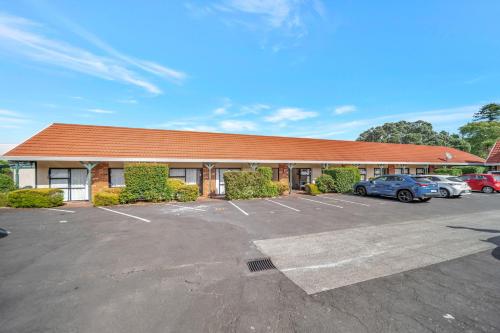 a building with cars parked in a parking lot at Tudor Court Motor Lodge in Auckland