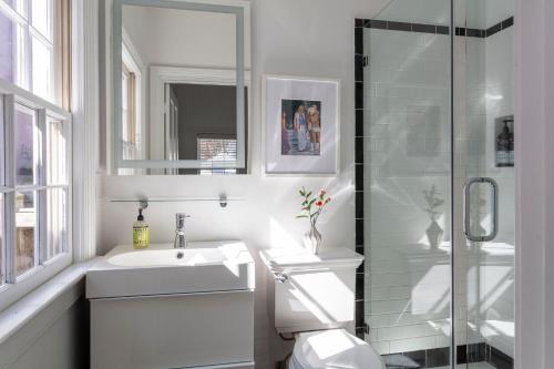 a white bathroom with a sink and a shower at Green Cottage at Casa Zoe in Charleston