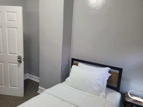 Schlafzimmer mit einem Bett mit weißer Bettwäsche und Kissen in der Unterkunft Chilltown in Wakefield