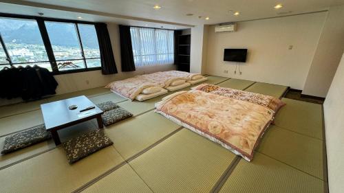 two beds in a large room with windows at 湯布院 旅館 やまなみ Ryokan YAMANAMI in Yufuin