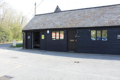 a black building with a door and windows at The Stables Lodge Stansted in Takeley