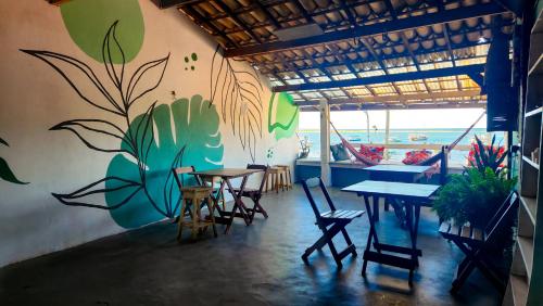 a restaurant with tables and chairs and a mural on the wall at Casa Aberta in Itacaré