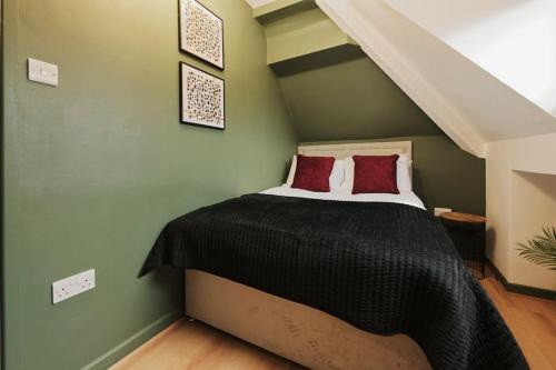 1 dormitorio con 1 cama con sábanas negras y almohadas rojas en Lamara Flat 3, Liverpool en Liverpool