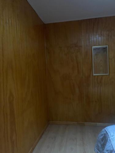 an empty room with wooden walls and a bed at Hospedaje Canela in Osorno