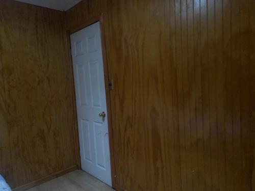 Habitación vacía con puerta blanca y paredes de madera. en Hospedaje Canela, en Osorno