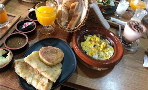 a wooden table with a plate of food with eggs and toast at Hotel Jnane riad in Marrakech