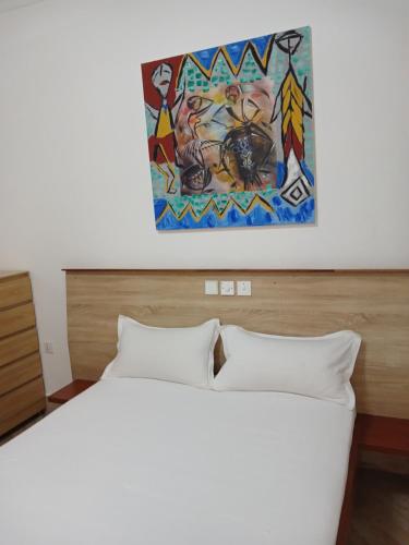 a bedroom with a bed and a painting on the wall at Queen's 2 BDR Appartments Accra in Chantan
