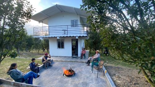 a group of people sitting around a fire in front of a house at Finca Peradise - Nuevo Colón in Nuevo Colón