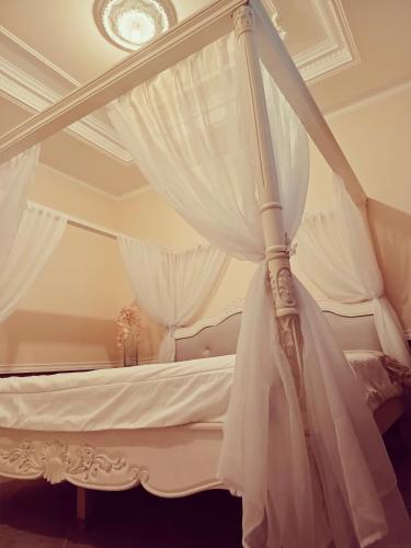 una cama blanca con dosel y cortinas blancas. en Hospedaje Riobamba, en Riobamba