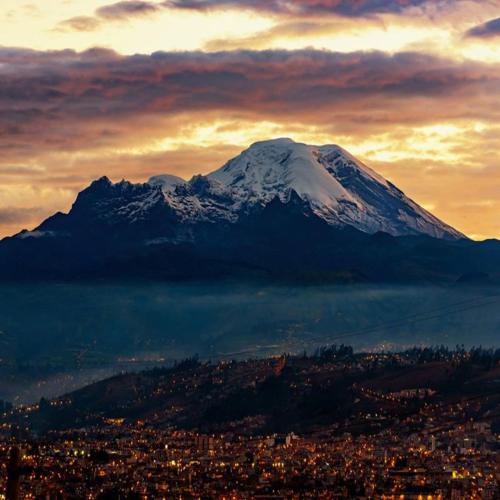 a snow covered mountain in front of a city at Hospedaje Riobamba in Riobamba