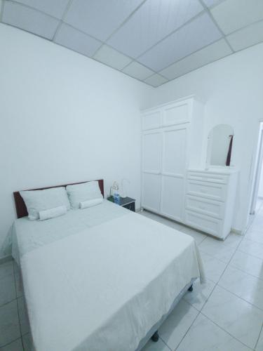 Acogedora casa en Lomas de Bella Vista في لا يونون: غرفة نوم بيضاء فيها سرير ابيض كبير