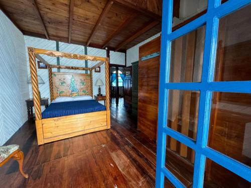a bedroom with a wooden bed with blue sheets at Hosteria Farallon Dillon in Ballenita