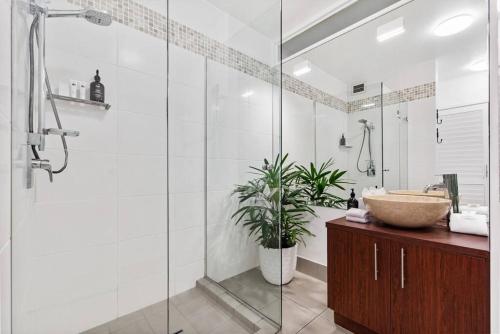 a bathroom with a sink and a glass shower at Noosa Tropical Beach Retreat ~ Walk to Everything in Noosa Heads