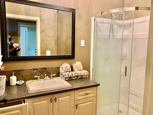 a bathroom with a sink and a shower with a mirror at Langley独立洗手间的一楼温馨客房 in Pitt Meadows