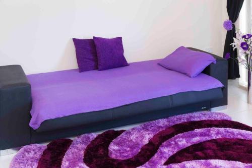 uma cama roxa com almofadas roxas e um tapete roxo em Schöne Ferienwohnung in San Tumas mit Grill und Terrasse em Marsaskala