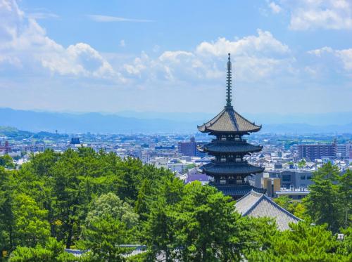 a building with a tower on top of a city at Henn na Hotel Premier Nara in Nara
