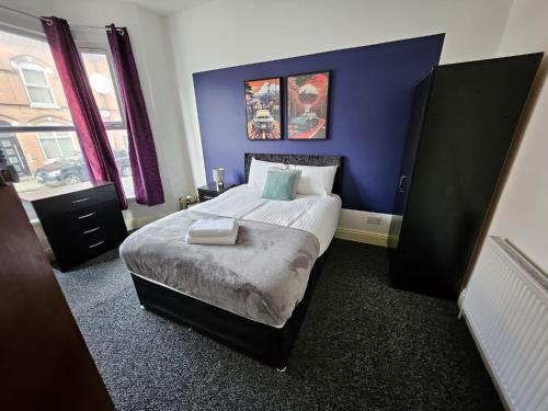 a bedroom with a large bed with a blue wall at Cannon Hill Shared House in Birmingham