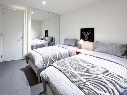 a bedroom with two beds and a mirror at Brilliant Quay Boulevard Apt in Werribee South