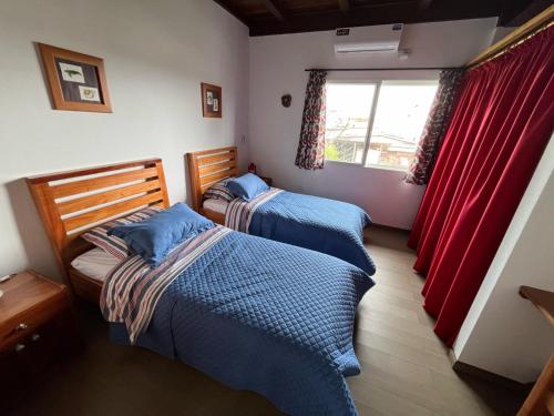 two beds in a bedroom with red curtains at German Home Tobias in Bahía de la Academia