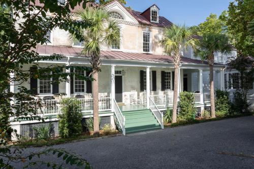 a white house with palm trees in front of it at Solarium at Cassa Zoe in Charleston