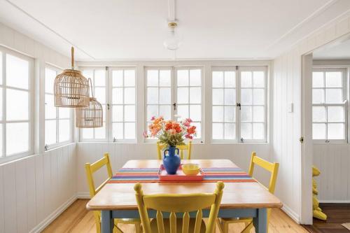 a dining room with a table with a vase of flowers at Camellia Cottage! CBD Diamond! in Toowoomba