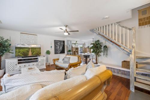 a living room with white furniture and a staircase at Cotton Tree Tranquil Gem Central Apartment in Maroochydore