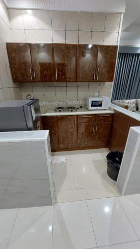 a kitchen with brown cabinets and a white tile floor at شقق القارات السبع المخدومة in Medina