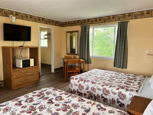 um quarto de hotel com duas camas e uma televisão em River forest inn em Belton