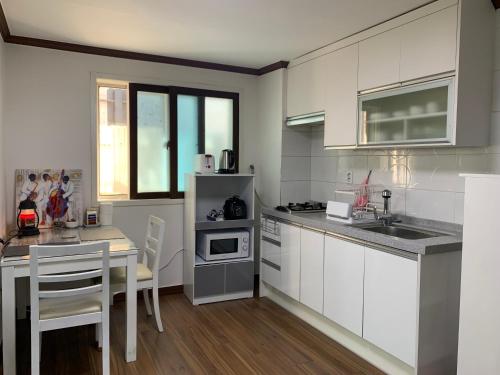 uma cozinha com armários brancos e uma mesa com cadeiras em Miranda House em Jeonju