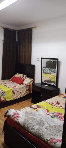 شقة مفروشة بعباس العقاد في القاهرة: غرفة نوم بسريرين وطاولة مع صورة