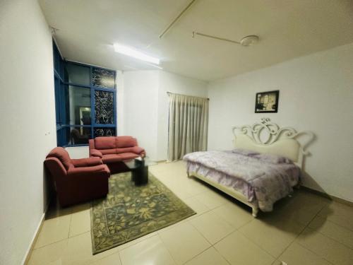 a bedroom with a bed and a chair and a window at Tranquil Haven:King Bed, Ensuite, Master Bedroom in Ajman 