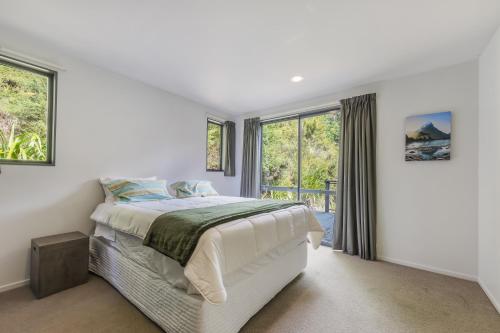a white bedroom with a bed and a window at Tepuia Daze - Havelock Holiday Home in Picton