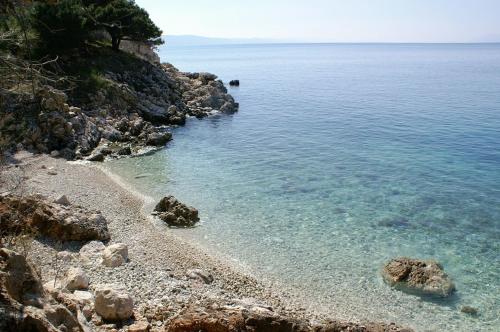 a beach with rocks and the clear blue water at Apartments by the sea Drasnice, Makarska - 22864 in Drasnice