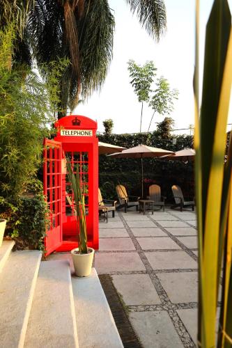 a red phone booth in a courtyard with tables and chairs at Hotel Grand Vista Cuernavaca in Cuernavaca