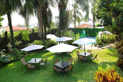 een groep tafels en stoelen met parasols bij Hotel Grand Vista Cuernavaca in Cuernavaca