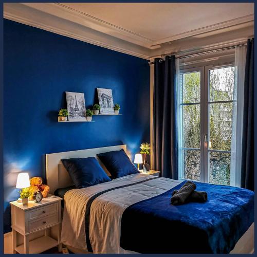 a blue bedroom with a bed and a window at Perle Haussmannienne 1900 - Cosy - Centre ville in La Garenne-Colombes