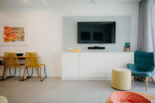 a living room with a tv and a table and chairs at Netanya Noosa Beachfront Resort in Noosa Heads